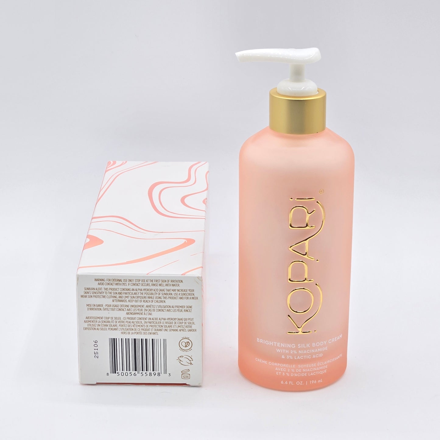 Kopari Brightening Silk Body Cream, 6.6 fl oz, in a frosted peach pump bottle with a gold cap, next to its white and peach patterned box.