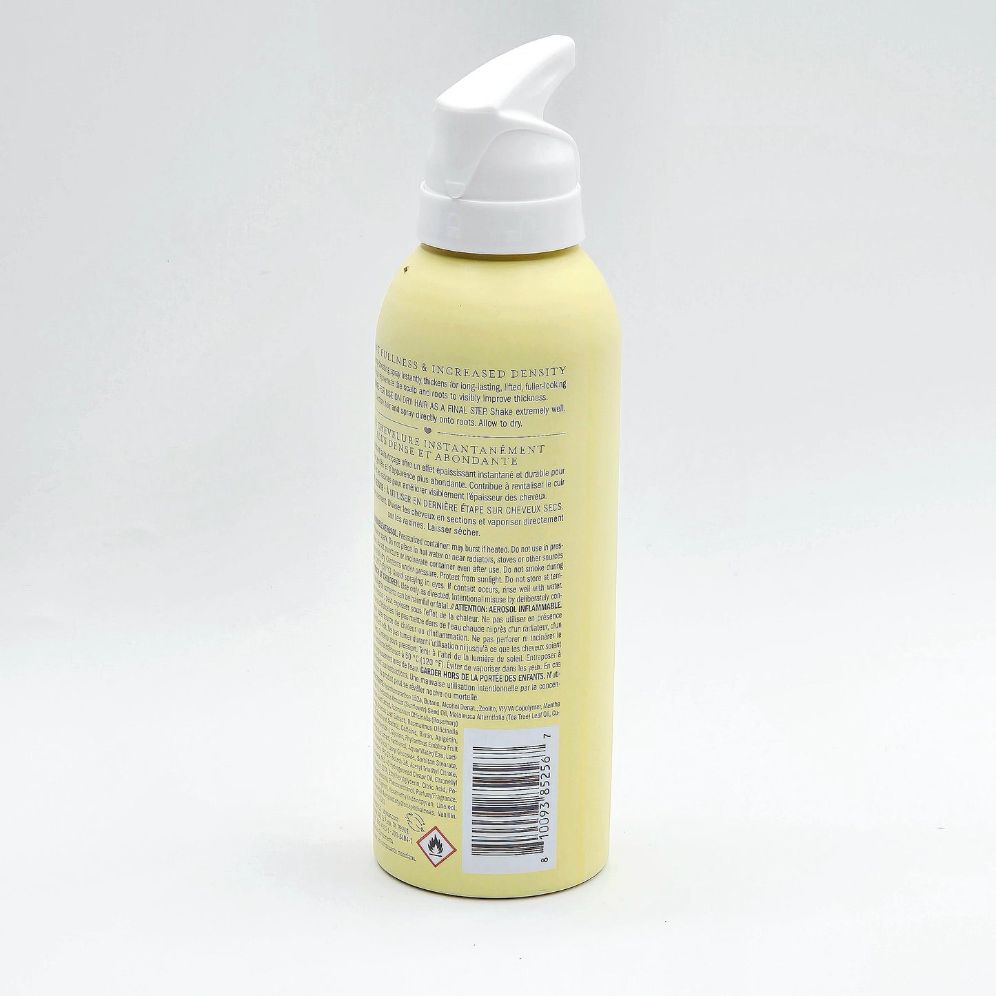 A pale yellow pump bottle of hair product shown from the back, featuring a white pump dispenser and a barcode label on a clean white background.