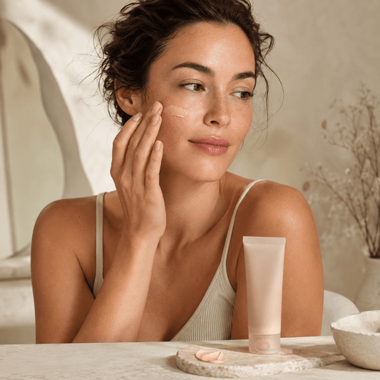 Woman blending sheer BB cream onto her cheek beside an unbranded complexion tube