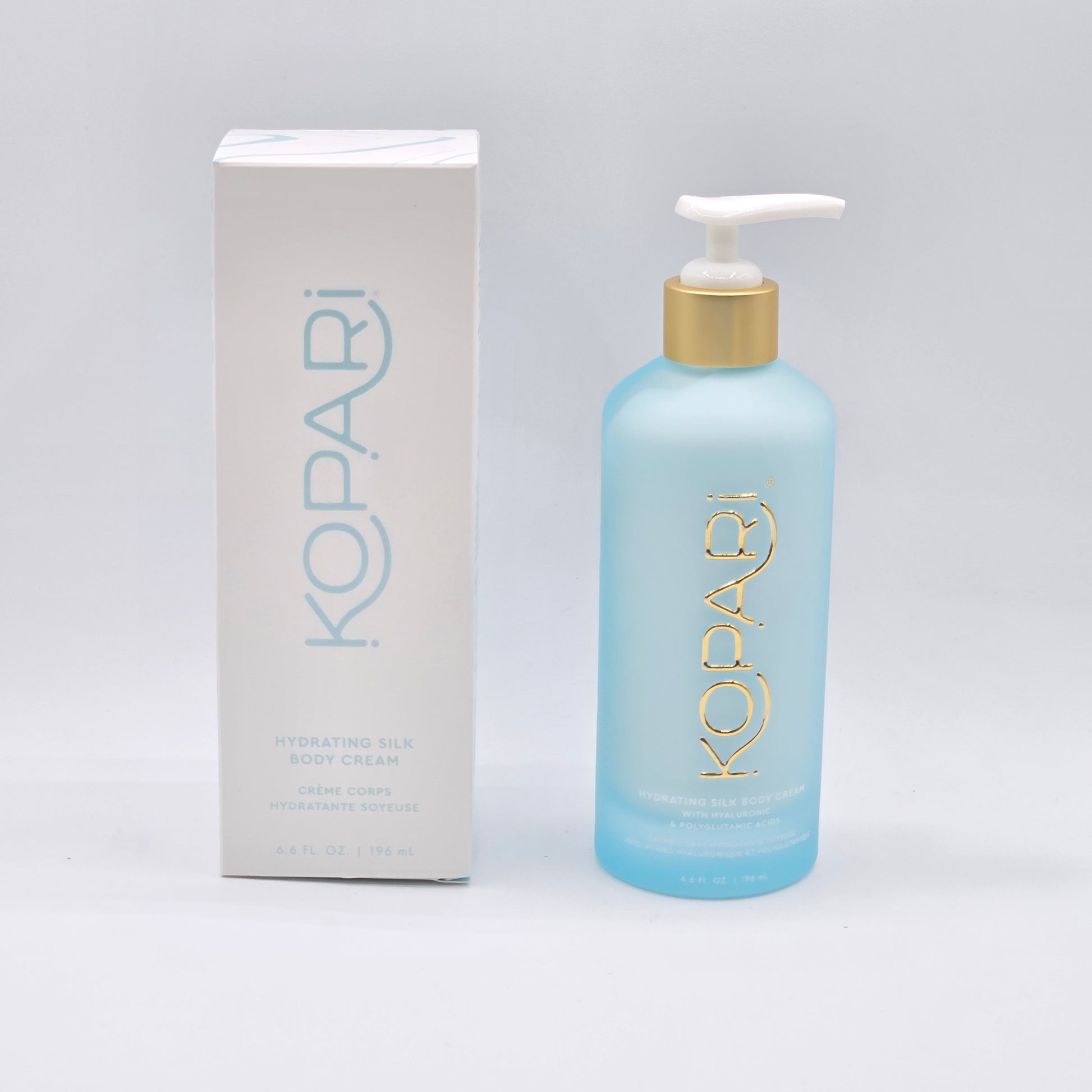 Kopari Hydrating Silk Body Cream: 6.6 fl oz light blue pump bottle with gold accents, beside its white box.