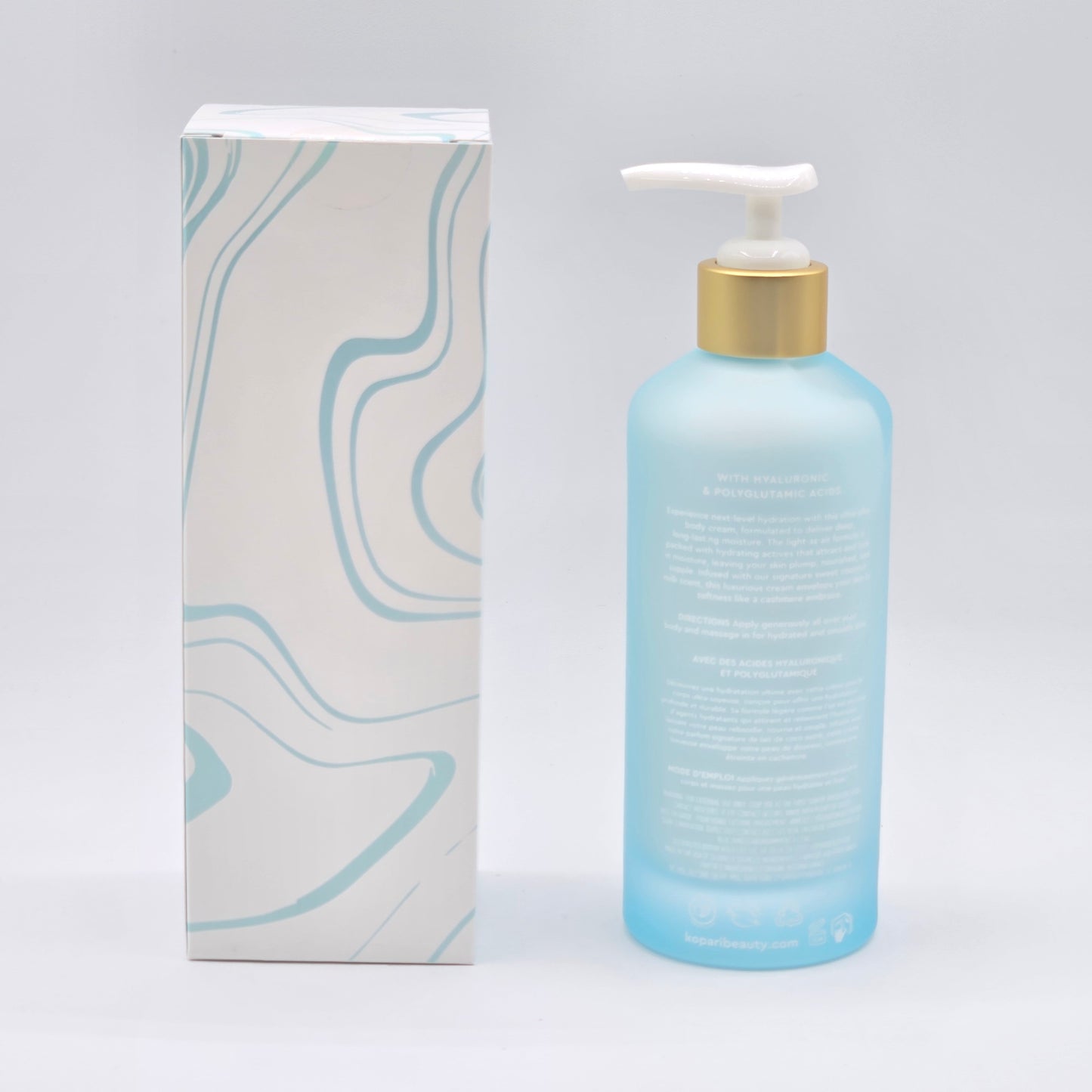 Kopari Hydrating Silk Body Cream: 6.6 fl oz blue bottle with gold pump next to a white box with blue waves.