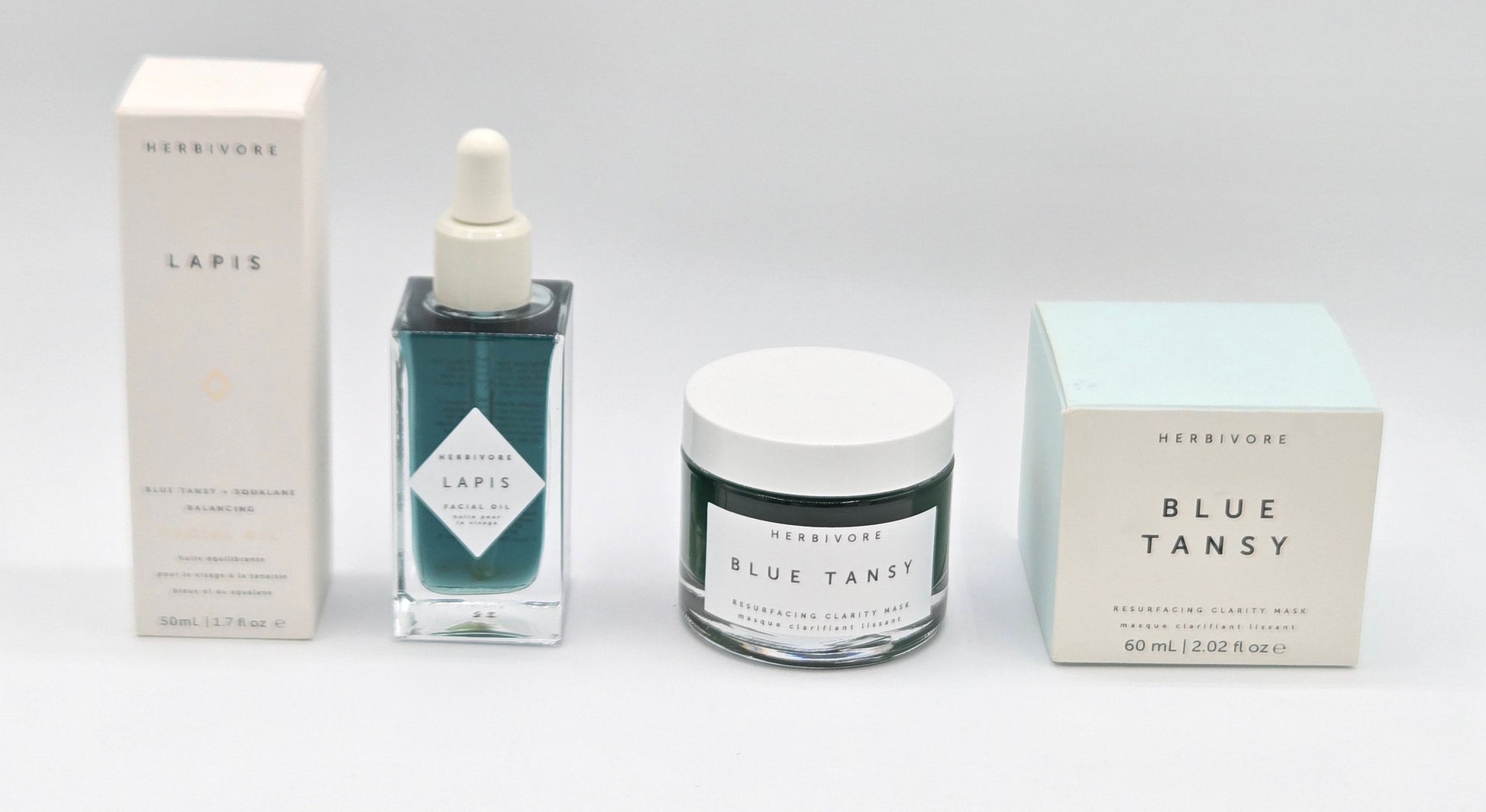 Herbivore Blue Tansy skincare products including a dropper bottle, jar, and boxes on a white background