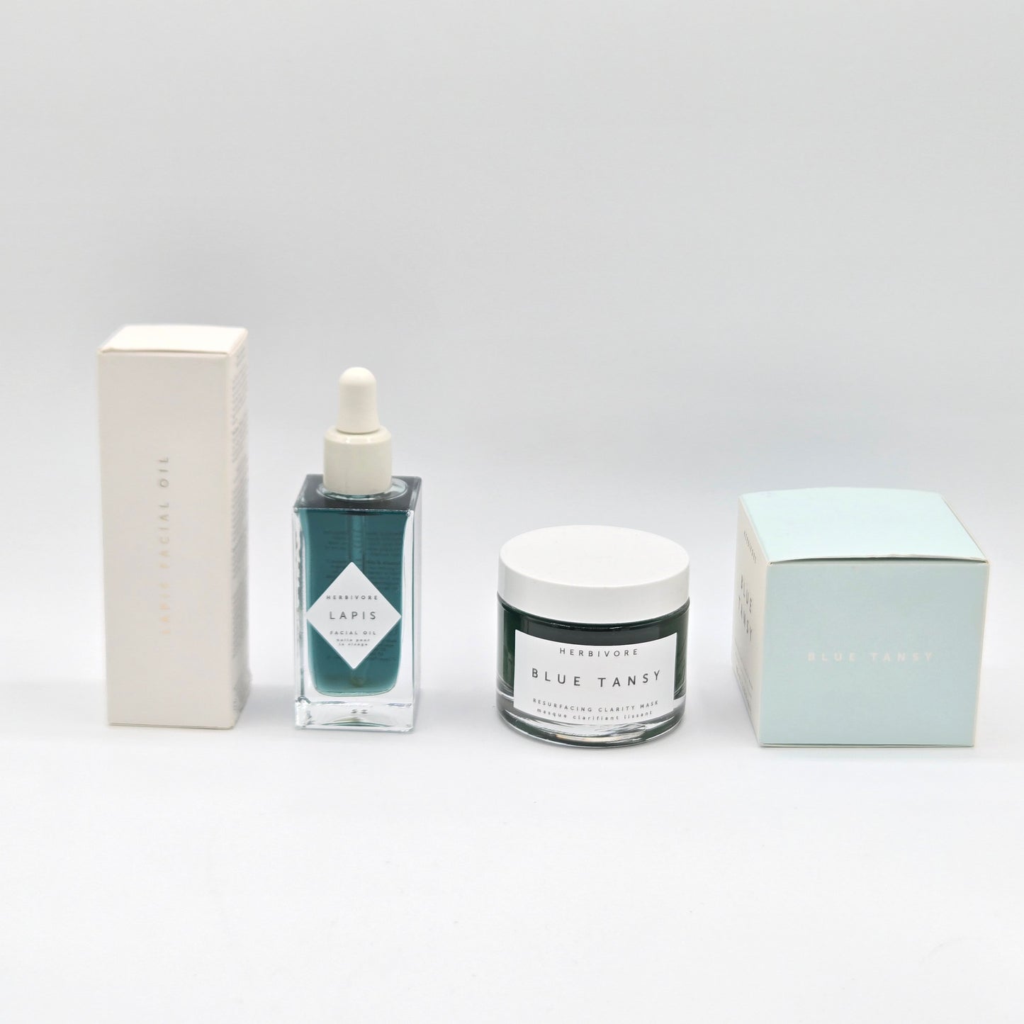 Set of skincare products including a bottle, jar, and boxes on a light gray background