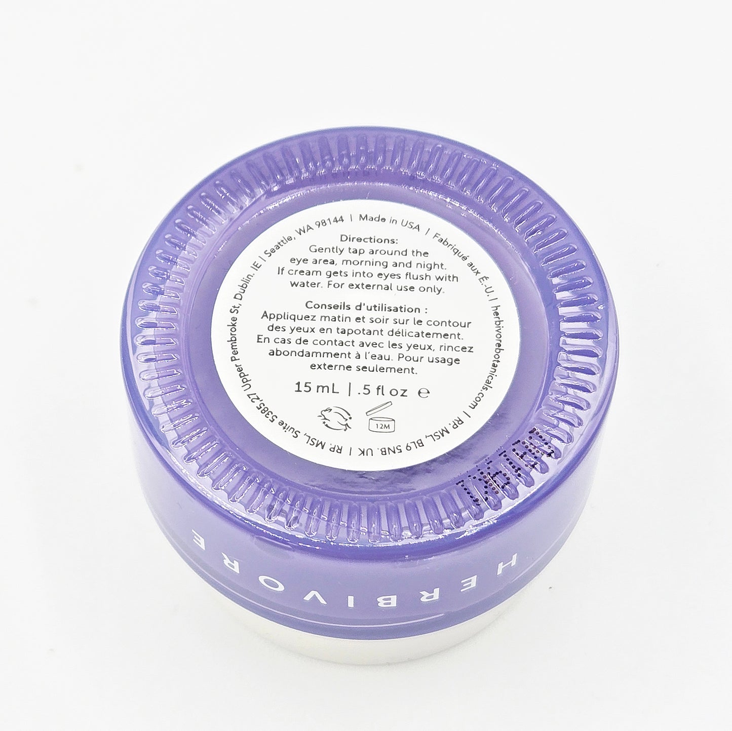 Herbivore eye cream jar with purple lid on a white background