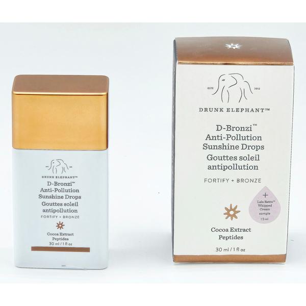 Drunk Elephant D-Bronzi Anti-Pollution Sunshine Drops in a white bottle with a gold cap, next to its matching box.