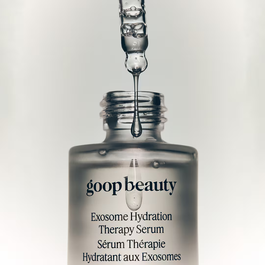 Close-up of a glass dropper releasing clear goop Beauty Exosome Hydration Therapy Serum above the open bottle.