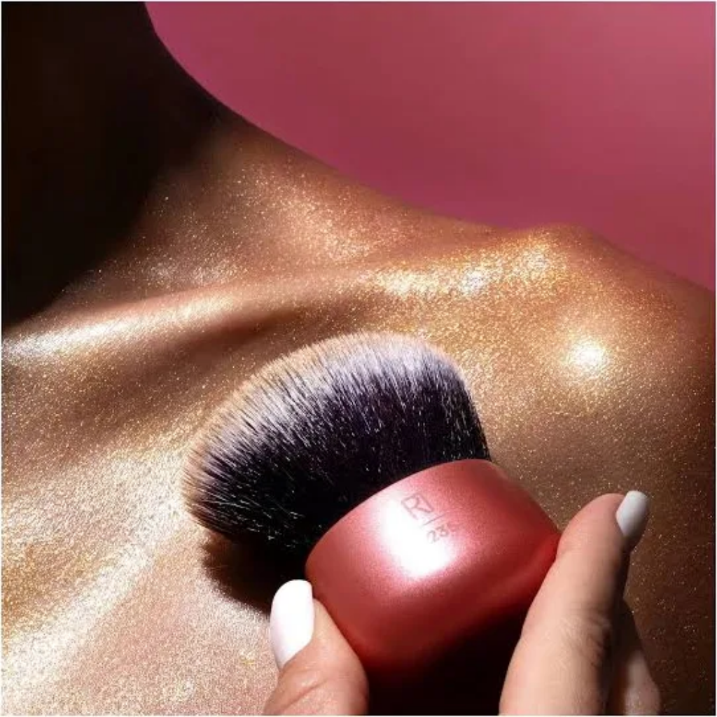 Brand application image showing kabuki brush blending body glow over a shoulder