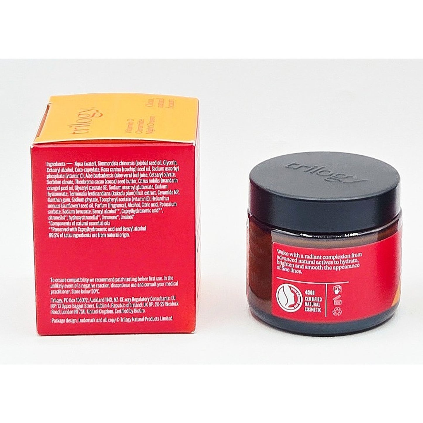 Jar of skincare product with red label and black lid next to its packaging box on a white background