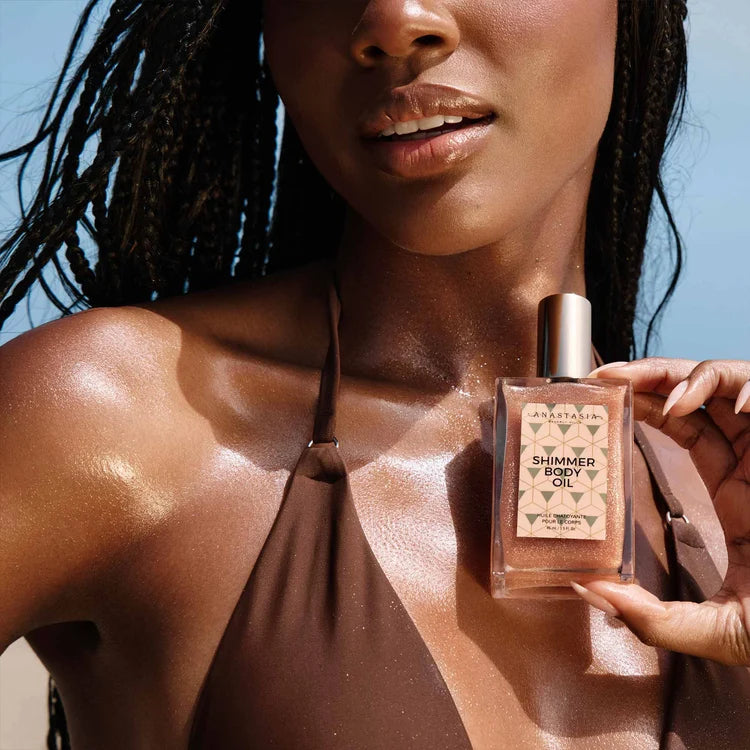 Model holding Rose Gold Shimmer Body Oil with shimmer visible on shoulders and chest