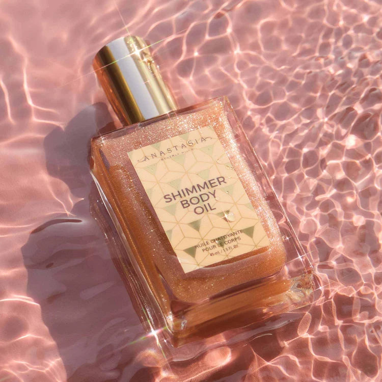 Anastasia Beverly Hills Rose Gold Shimmer Body Oil bottle in pink reflected light