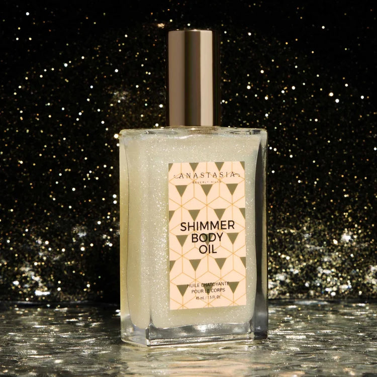 Anastasia Beverly Hills White Shimmer Body Oil bottle against gold sparkles