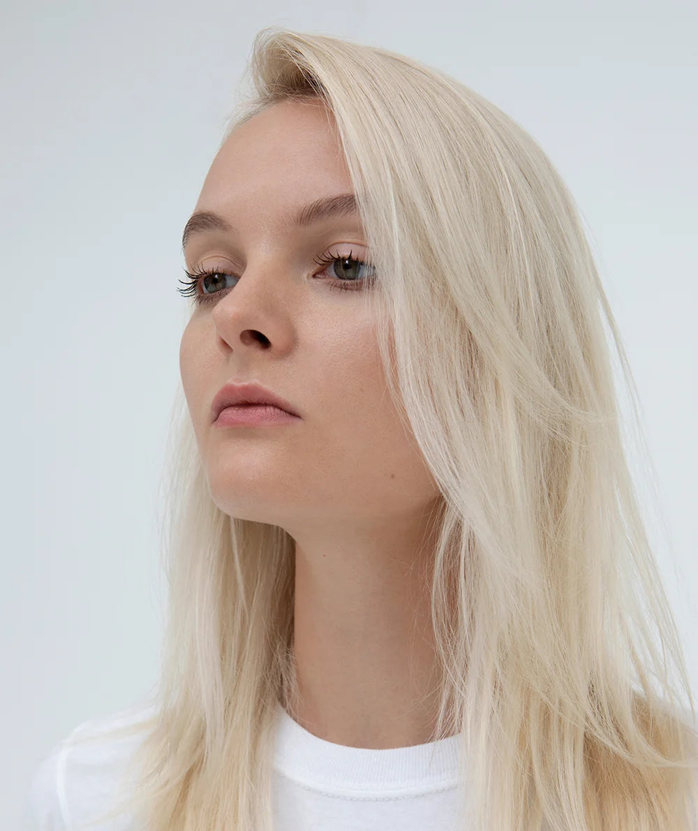 Model with smooth, straight blonde hair in an R+Co CENTERPIECE styling photo.