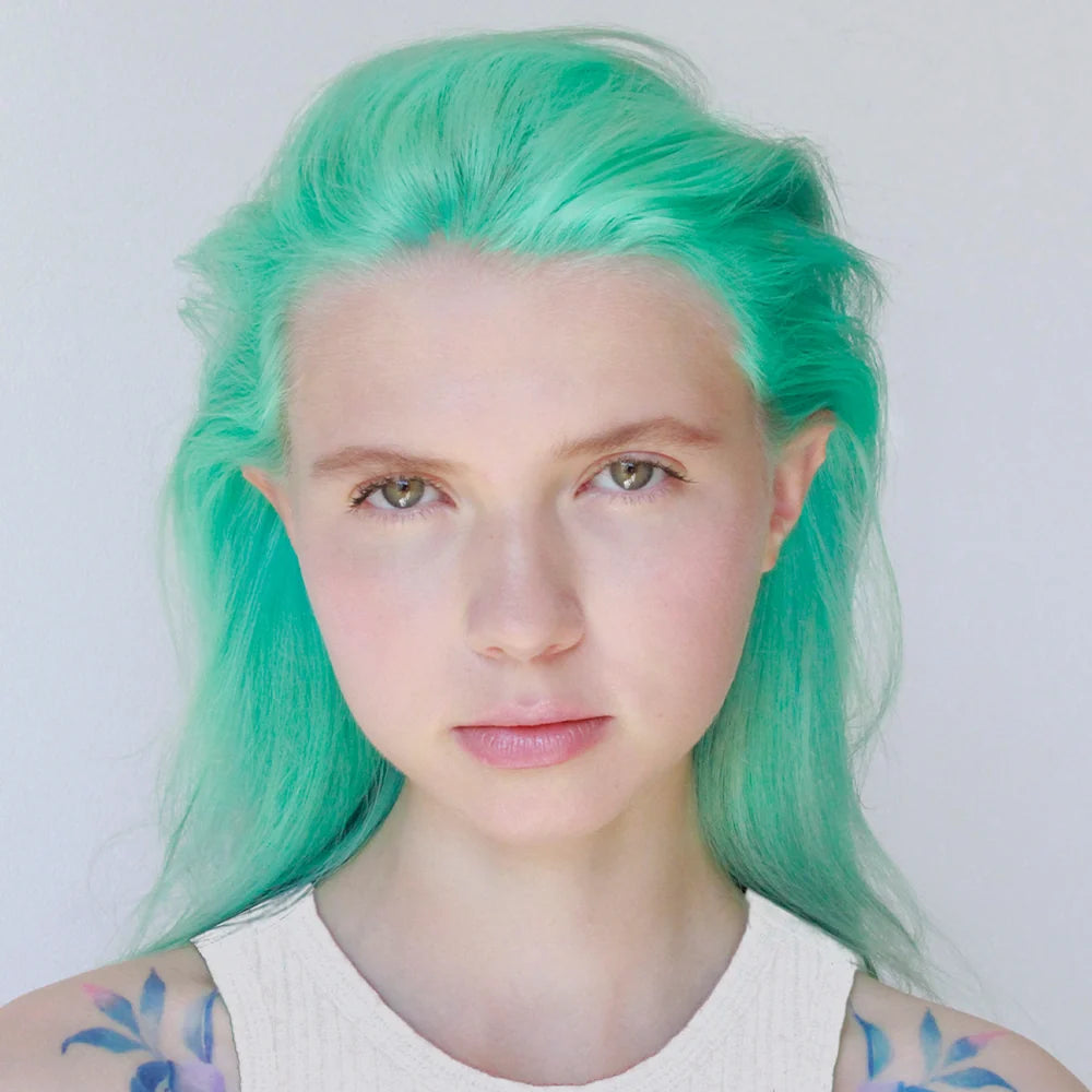 Model with bright mint-green hair in an R+Co Gemstone Color Protect Masque promotional image