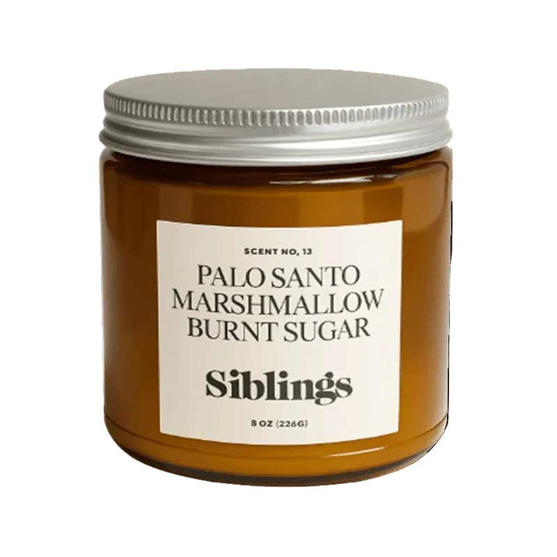 Siblings No. 13 candle, 8 oz, in an amber jar with silver lid and palo santo, marshmallow and burnt sugar label.