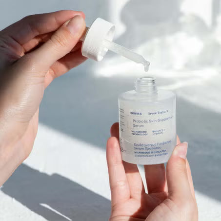 Hands holding a Korres Greek Yoghurt serum bottle and dropper