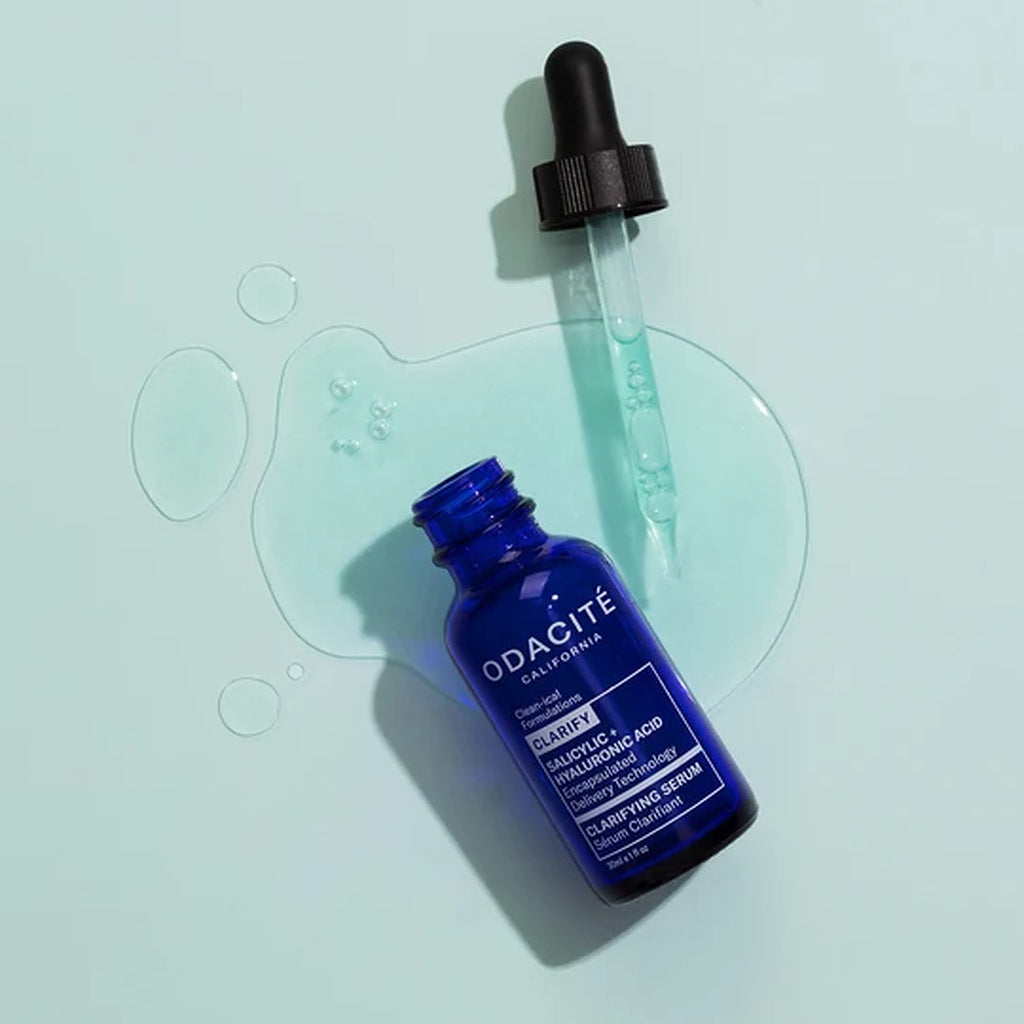 Odacité Clarifying Serum 30 mL bottle and dropper on pale blue serum texture background