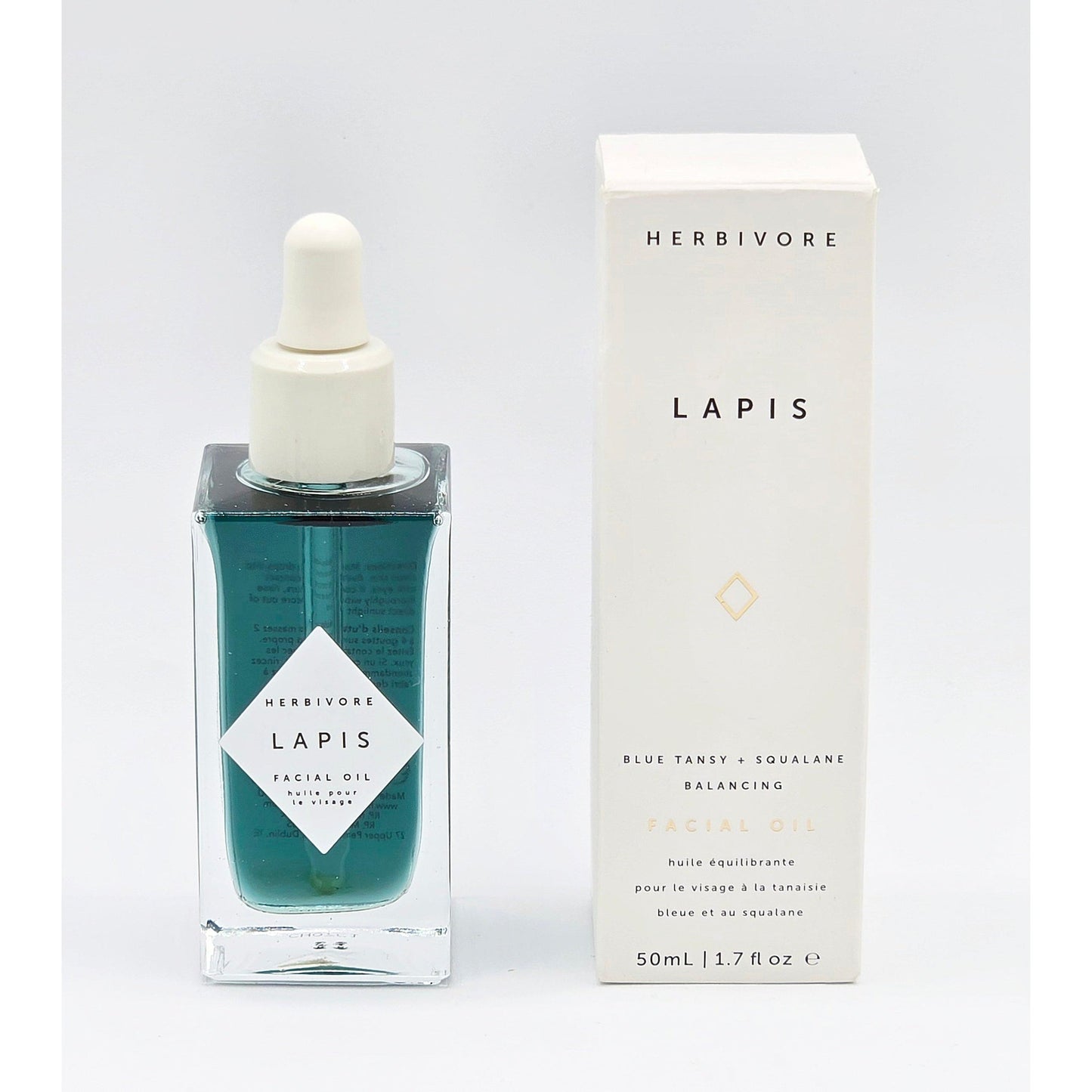 Herbivore Botanicals Lapis Balancing Facial Oil in a square blue glass bottle with dropper, next to its white box.