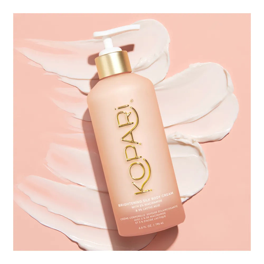 Kopari Brightening Silk Body Cream bottle displayed over swirls of cream on a peach background